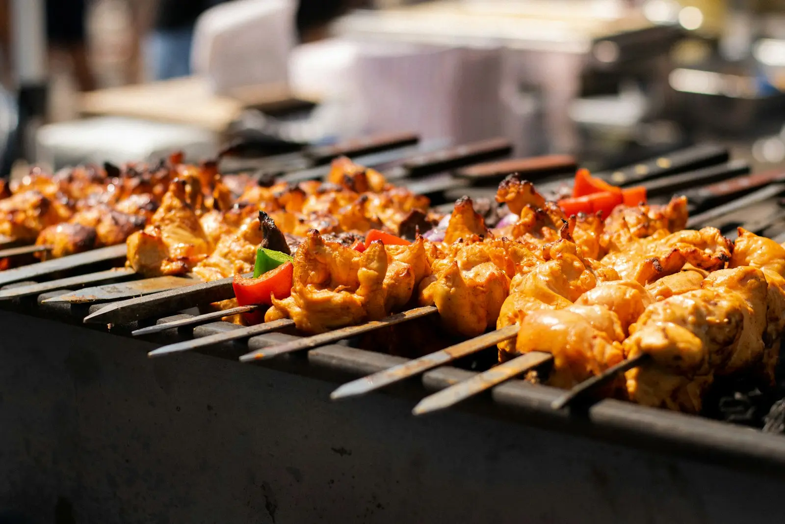 Chicken tikka skewers cooking on a charcoal grill
