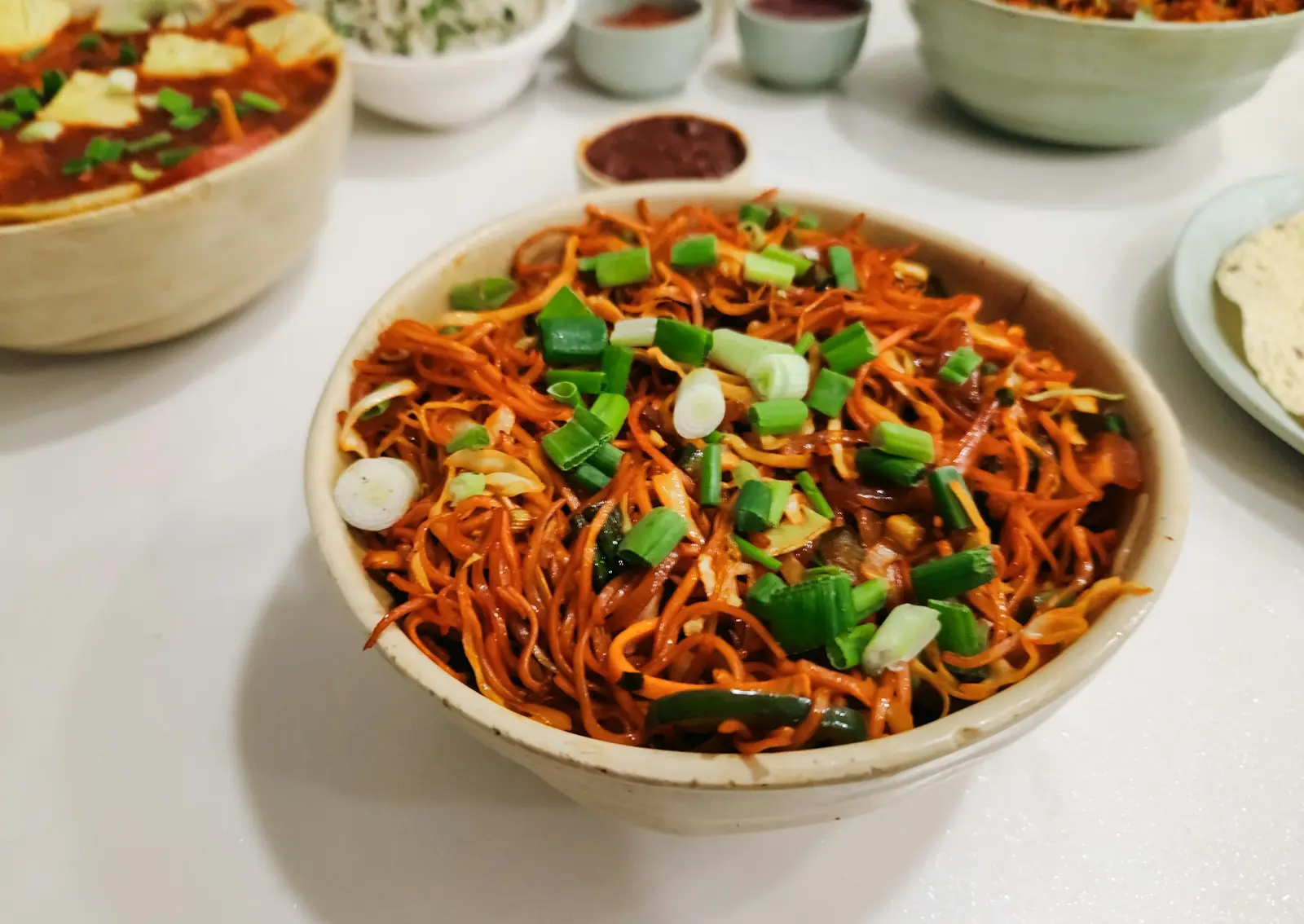 Bowl of Indo-Chinese stir-fried noodles topped with spring onions