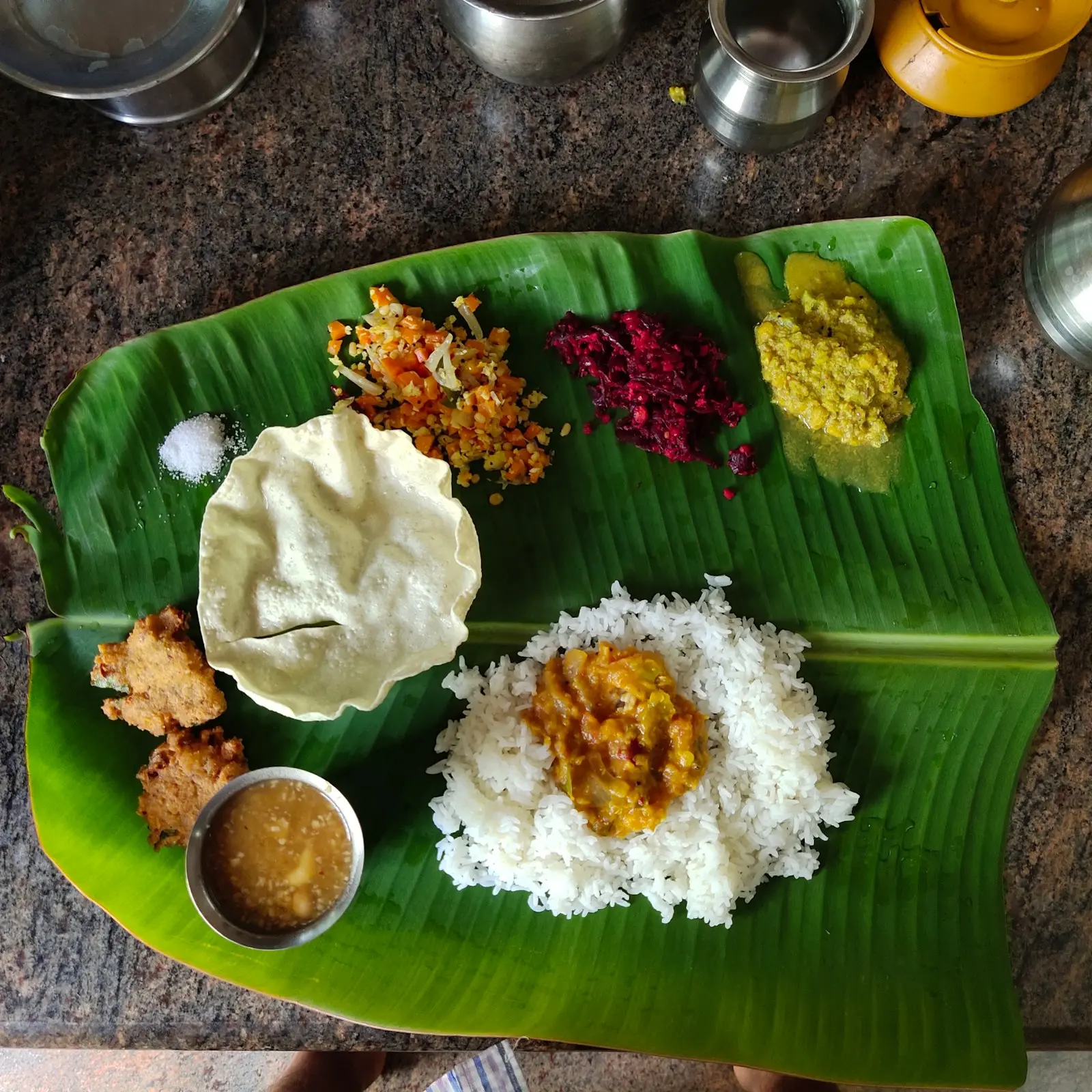 South Indian meal served on a banana leaf with rice, sambar, poriyal and appalam