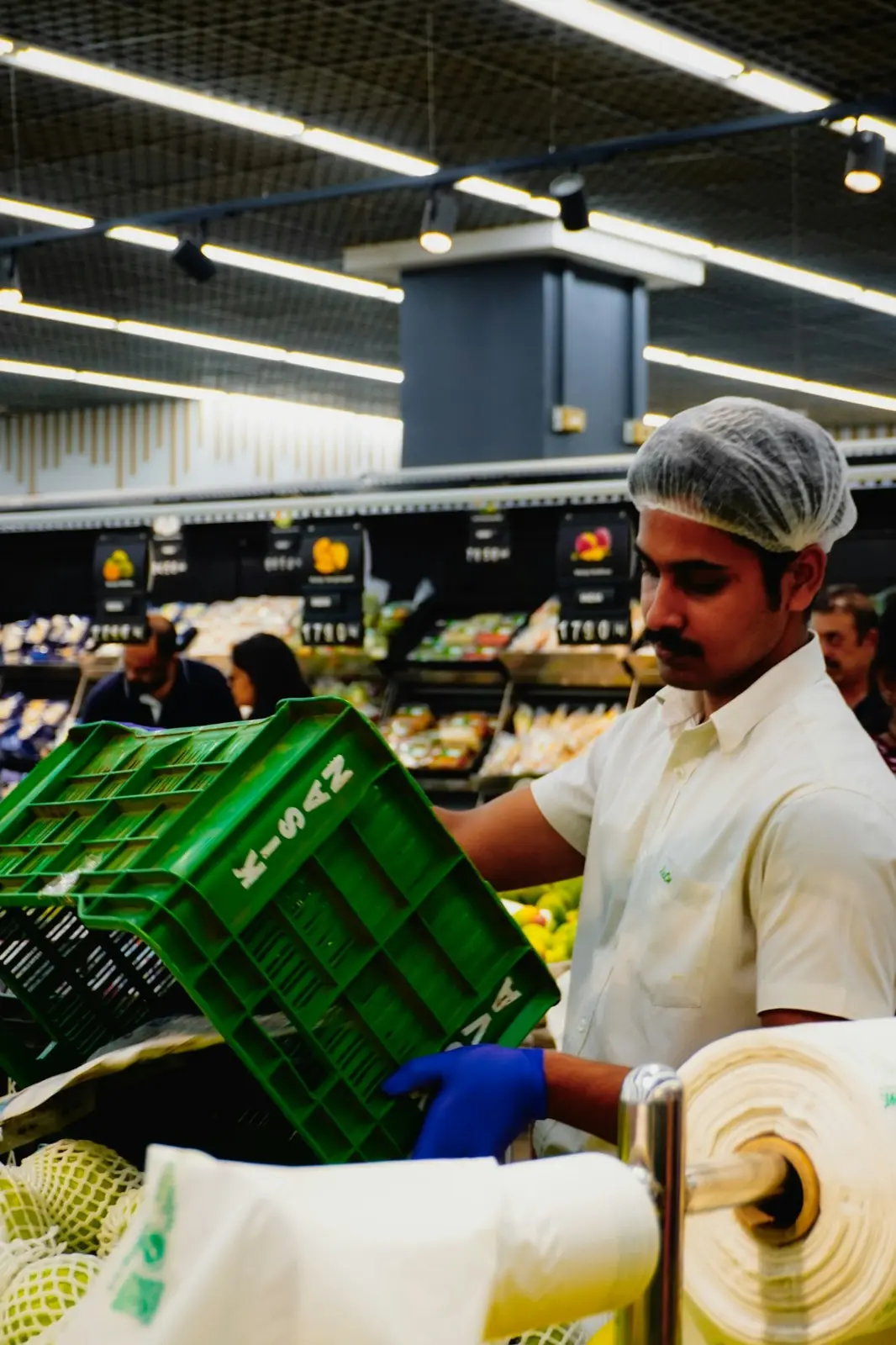 Store worker in a hairnet stocking fresh produce